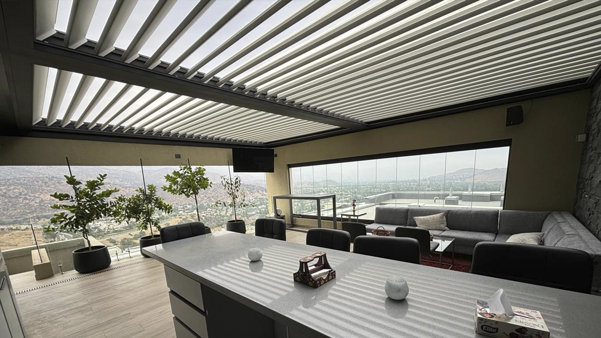 Pérgola bioclimática con aspas abiertas sobre una terraza cerrada con cristal